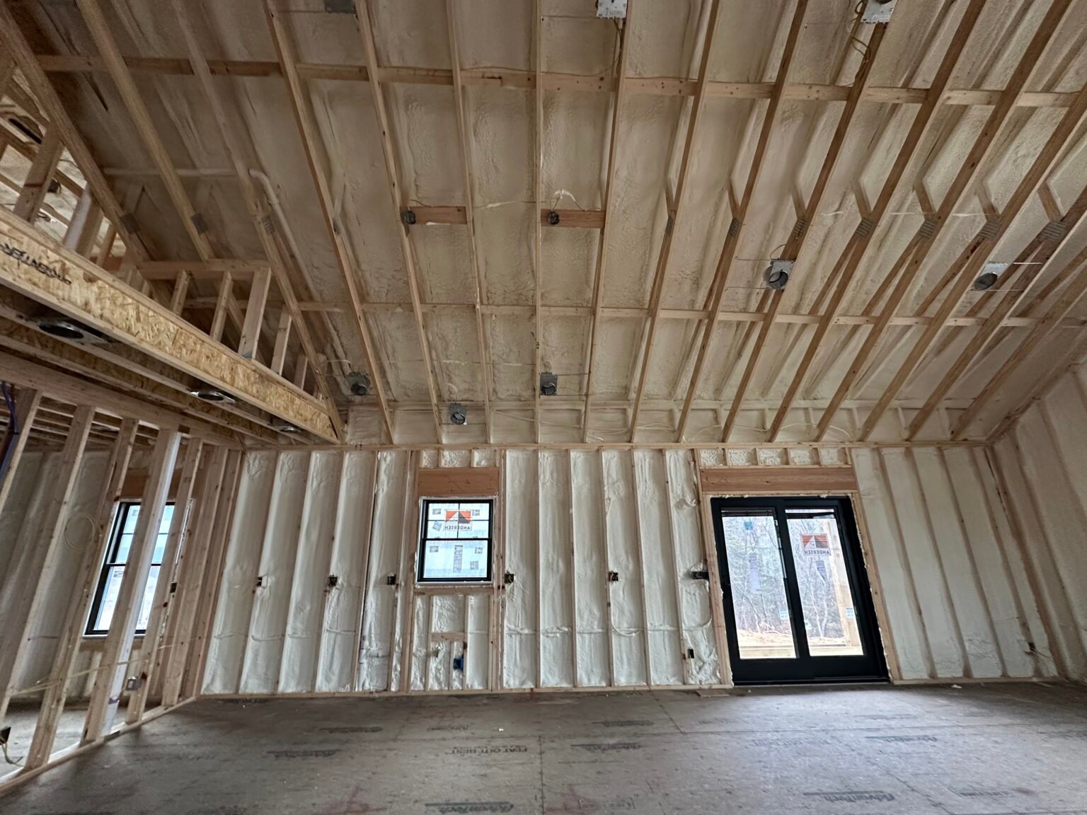 Open-cell spray foam insulation installed along the roofline and walls of a framed building